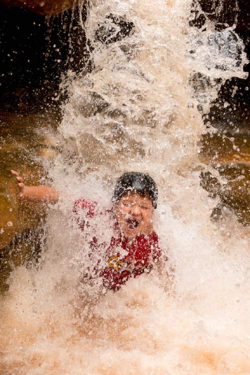 Trent Nelson  |  The Salt Lake Tribune
Paolo Zambrano cools off in a waterfall on the Sulphur Creek trail, a 5-mile slot canyon hike in Capitol Reef National Park, Saturday August 1, 2015.