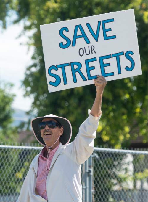 Rick Egan  |  The Salt Lake Tribune

Timothy Dvorsky holds a sign in protest along with other South Salt Lake residents. They marched to State Street to demonstrate their opposition to the noise, inconvenience and increased traffic caused by the closure of Burton and Truman Avenues, Saturday, Aug. 8, 2015.