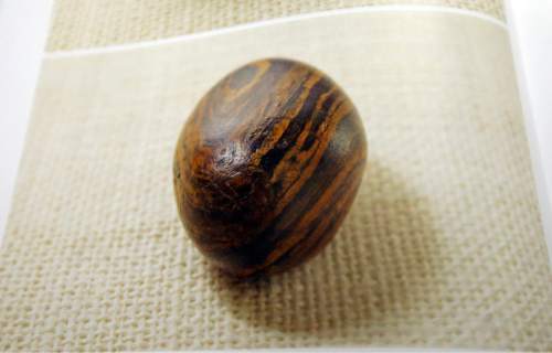 A picture of a smooth, brown, egg-sized rock is shown in the printer's manuscript of the Book of Mormon following a news conference Tuesday, Aug. 4, 2015, at The Church of Jesus Christ of Latter-day Saints Church History Library, in Salt Lake City. The Mormon church for the first time is publishing photos of a small sacred stone it believes founder Joseph Smith used to help translate the story that became the basis of the religion. The Mormon church is taking another step in its push to be more transparent, and is releasing more historical documents that shed light on how Joseph Smith formed the religion. (AP Photo/Rick Bowmer)