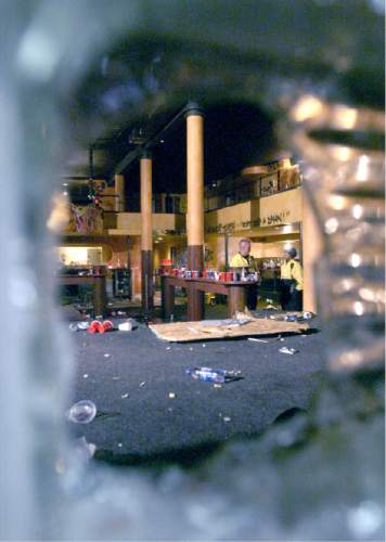 View of interior of the Zephyr club from the side walk looking through a hole in a glass block that back the stage.  Some of the damage caused by a final night Halloween bash at the Zephyr Club.  Two unidentified SlC Police officers survey the scene in the background 11/01/03 Stephen Zusy/ Salt lake Tribune