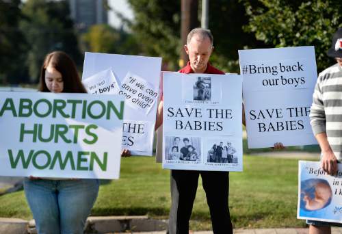 Scott Sommerdorf   |  The Salt Lake Tribune
Abortion protestors hold signs as they bow their heads while they listen to Robert Woods read a prayer on Saturday outside the Salt Lake City Planned Parenthood as part of a nationwide protest. Organizers say a coalition of 60 groups planned to protest at more than 300 Planned Parenthood facilities in the nation.