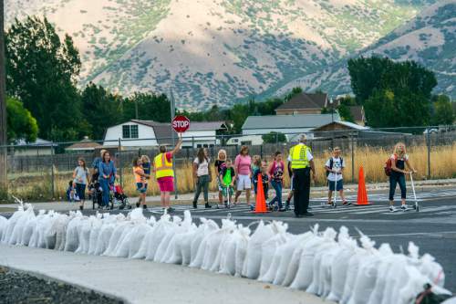 Chris Detrick  |  The Salt Lake Tribune
Kids walk home from school near sandbags on Salam Canal Road to help divert water from the West Salem Canal breach Tuesday August 25, 2015.