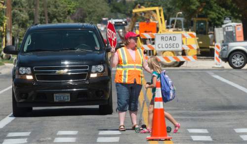 Steve Griffin  |  The Salt Lake Tribune

Construction continues, back, on 2100 east near 1800 south as students cross the street at Dilworth Elementary School in Salt Lake City, Monday, August 24, 2015.  Dilworth is one of a handful of elementary schools where the road is ripped up near the front of the school.