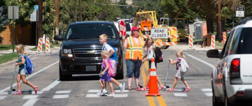 Steve Griffin  |  The Salt Lake Tribune

Construction continues, back, on 2100 east near 1800 south as students cross the street at Dilworth Elementary School in Salt Lake City, Monday, August 24, 2015.  Dilworth is one of a handful of elementary schools where the road is ripped up near the front of the school.