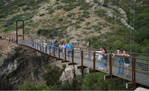 Steve Griffin  |  The Salt Lake Tribune
Builders, sponsors, supporters and Draper City officials walk across the new pedestrian suspension bridge that spans 185 feet across Bear Canyon and connects the Bonneville Shoreline Trail in Draper, Tuesday, August 25, 2015.
