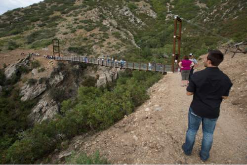 Steve Griffin  |  The Salt Lake Tribune

Builders, sponsors, supporters and Draper City officials walk across the new pedestrian suspension bridge that spans 185 feet across Bear Canyon and connects the Bonneville Shoreline Trail in Draper, Tuesday, August 25, 2015.