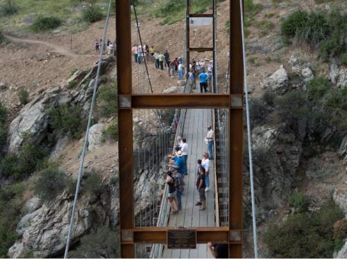 Steve Griffin  |  The Salt Lake Tribune

Builders, sponsors, supporters and Draper City officials walk across the new pedestrian suspension bridge that spans 185 feet across Bear Canyon and connects the Bonneville Shoreline Trail in Draper, Tuesday, August 25, 2015.