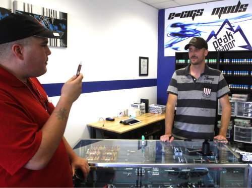 Rick Egan  | The Salt Lake Tribune 

Corey Peay purchases flavors for his e-cigarette from Jake Simpson, owner of Peak Vapor, Monday, September 30, 2013.  Peay purchased  PB & Chocolate, Gummi Bear, and Rockstar flavored liquid for his e-cigarette.