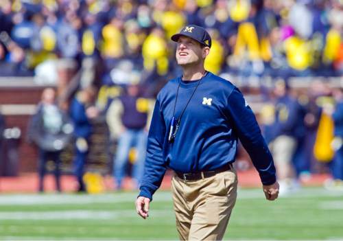 FILE - In this April 4, 2015, file photo, Michigan head coach Jim Harbaugh walks the field between downs during the NCAA college football team's spring game in Ann Arbor, Mich. Now Harbaugh will finally begin coaching the Wolverines in some actual games _ but no matter how this first season in Ann Arbor goes, the quirky, khaki-wearing coach has unified a fractured Michigan fan base.  (AP Photo/Tony Ding, File)