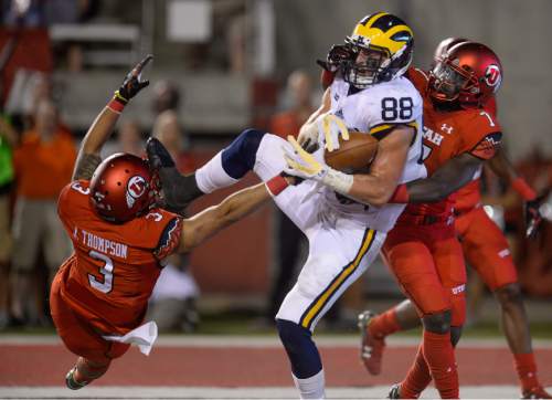 Francisco Kjolseth | The Salt Lake Tribune
Michigan Wolverines tight end Jake Butt (88) pulls in a touchdown despite efforts by Utah Utes defensive back Jason Thompson (3) and Utah Utes defensive back Andre Godfrey (7) in game action at Rice Eccles Stadium on Thursday, Sept. 3, 2015.