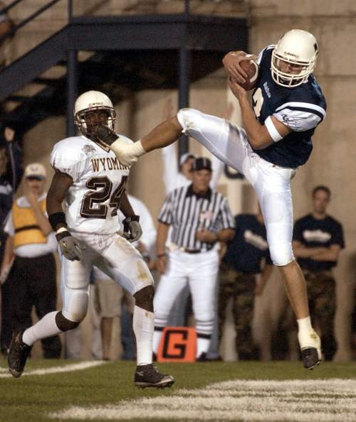 Rick Egan  |  The Salt Lake Tribune 

USU's Kevin Curtis leaps up to make a catch for a touchdown for the Aggies, as Wyoming defender #24 Eric Lee looks on helplessly in Logan September 22, 2001.