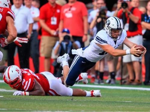 BYU quarterback Tanner Mangum (12) leaps for extra yards after being tripped by Nebraska defensive end Greg McMullen (90) during the second half of an NCAA college football game in Lincoln, Neb., Saturday, Sept. 5, 2015. BYU won 33-28. (AP Photo/Nati Harnik)
