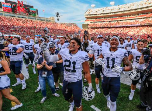 BYU players including linebacker Harvey Langi (21) and wide receiver Terenn Houk (11) celebrate their 33-28 win over Nebraska in an NCAA college football game in Lincoln, Neb., Saturday, Sept. 5, 2015. (AP Photo/Nati Harnik)