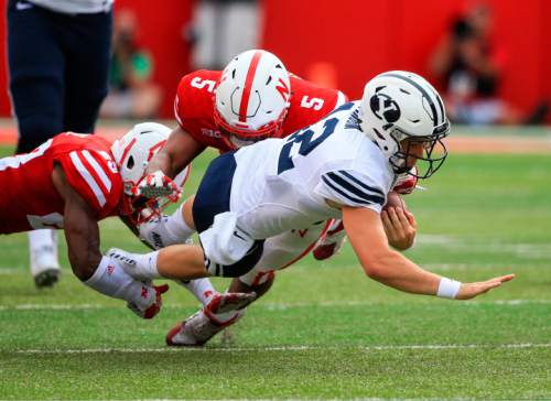 BYU quarterback Tanner Mangum (12) is tackled by Nebraska linebacker Dedrick Young (5) and cornerback Daniel Davie, left, during the first half of an NCAA college football game in Lincoln, Neb., Saturday, Sept. 5, 2015. (AP Photo/Nati Harnik)
