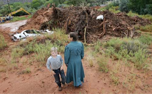 People look over debris and the remains of a car following a flash flood Tuesday, Sept. 15, 2015, in Colorado City, Ariz. Officials say the bodies of two people killed in flash flooding in southern Utah were recovered in Arizona about two and a half miles downstream, while the bodies of six others were recovered in Utah. (AP Photo/Rick Bowmer)