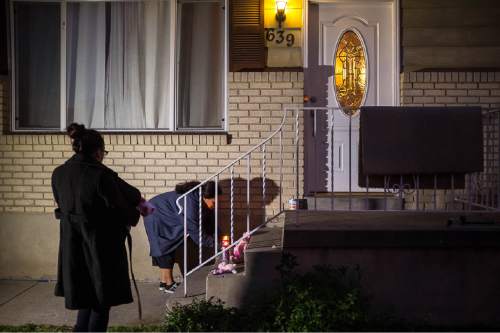 Trent Nelson  |  The Salt Lake Tribune
A woman leaves candles on the porch of the home of three homicide victims in Salt Lake City, Saturday September 19, 2015. Two of the three people found dead in the northwest Salt Lake City home were identified as Heike Poike, 50, and her 2-month-old granddaughter, Lyrik Poike. The male victim has not been identified.