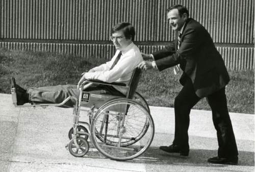 Tribune file photo
Mark Hofmann being pushed in wheel chair by his father.