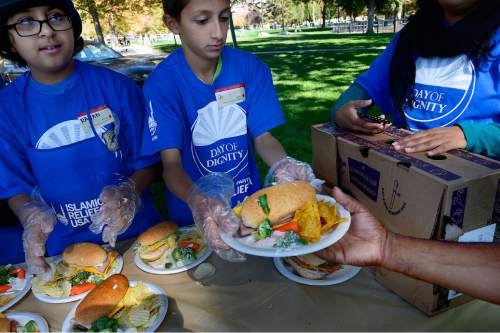 Scott Sommerdorf   |  The Salt Lake Tribune
Omar Khan, right, with the Islamic Relief Society hands out meals at the "Day of Dignity" in Pioneer Park, Sunday, October 11, 2015.