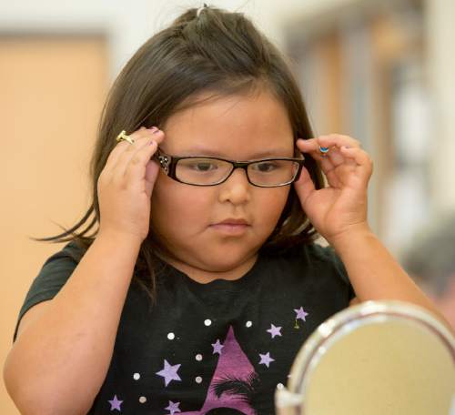 Rick Egan  |  The Salt Lake Tribune

Tareva-Chiné Kinney checks out her new glasses in the mirror, at Monument Valley Elementary School, Friday, September 25, 2015.