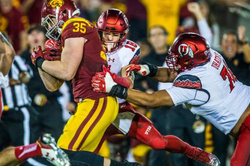 Chris Detrick  |  The Salt Lake Tribune
Utah Utes wide receiver Britain Covey (18) and Utah Utes offensive lineman Salesi Uhatafe (74) tackle USC Trojans linebacker Cameron Smith (35) after Smith intercepted the ball during the game at the Los Angeles Memorial Coliseum Saturday October 24, 2015.
