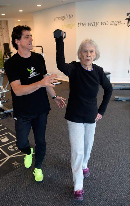Al Hartmann  |  The Salt Lake Tribune
Fitness trainer Paul Holbrook coaches 86-year-old Jinnah Kelson as she walks with a barbell overhead back and forth across the gym to work on balance and core strength at The Age Performance center in Sugarhouse Tuesday Nov. 10.  The center is celebrating its 10th anniversary of training older adults with specific strength programs.