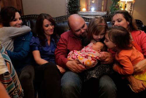 Leah Hogsten  |  The Salt Lake Tribune
Polygamist Joe Darger and his wives l-r Alina, Valerie and Vicki watch as daughters Krista, 4, and Victoria, 3, kiss their 3-day old sister Alexandra Tess, the newest member of the family. The Darger's celebrated the ruling handed down by U.S. District Court judge Clark Waddoups that key parts of Utah's polygamy laws are unconstitutional, December 13, 2013. "For the first time in my lifetime--and in the last 100 years, we don't have a cloud over our heads," said Joe of the ruling. "This is historic."