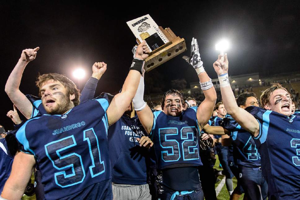 Trent Nelson  |  The Salt Lake Tribune
Juan Diego players hold the championship trophy after defeating Morgan in the 3A high school football championship game at Weber State in Ogden, Saturday November 14, 2015. Juan Diego's Paul Neeley (51), Juan Diego's Jorge Rico (52), Juan Diego's Danny Wilson (3).