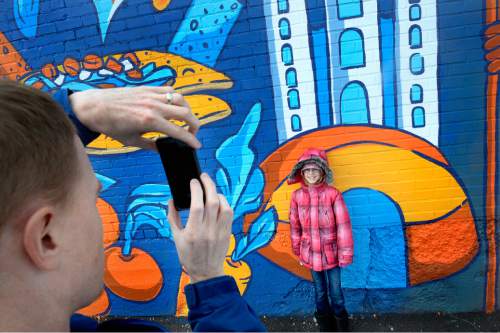 Scott Sommerdorf   |  The Salt Lake Tribune
Ben Arkell makes a photo of his daughter Kamri, 8, in front of the part of mural she worked on. Roger Whiting teamed up with Local First Utah and independent businesses including Tanner Frames and Mini's Cupcakes to kick off this year's Small Business Saturday, Saturday, November 28, 2015.