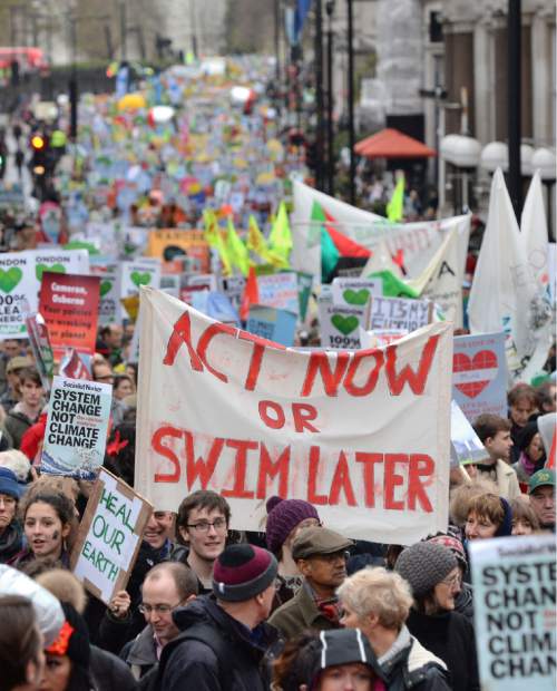 Campaigners hold a banner calling for everybody to act now or swim later, as demonstrators move through the streets of central London, campaigning for ambitious action to tackle climate change, Sunday Nov. 29, 2015. Campaigners want the Government and other countries to agree on a deal that will shift the world to renewable energy and protect people from the impacts of climate change. (Dominic Lipinski  / PA via AP) UNITED KINGDOM OUT - NO SALES - NO ARCHIVES