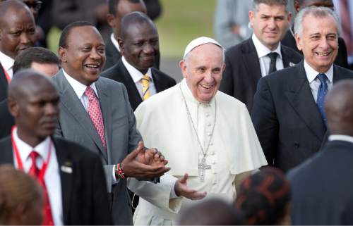 Pope Francis, center, is accompanied by Kenya's President Uhuru Kenyatta, left, and Deputy President William Ruto, center-left, on his arrival at the airport in Nairobi, Kenya Wednesday, Nov. 25, 2015. Pope Francis left Wednesday for his first-ever visit to the continent, a whirlwind pilgrimage to Kenya, Uganda and the Central African Republic, bringing a message of peace and reconciliation to an Africa torn by extremist violence. (AP Photo/Ben Curtis)