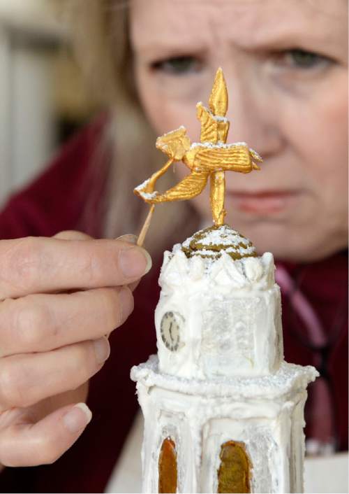 Al Hartmann  |  The Salt Lake Tribune
Robin Radcliff, culinary student at the Women's Correctional puts angel on the steeple of the Nauvoo Temple.  It's a part of a massive gingerbread display before being transported to the South Towne Center and donated to the Festival of Trees.  This year's theme is Utah History, featuring the Nauvoo Temple, Mormon wagon train and the Salt Lake Temple.
