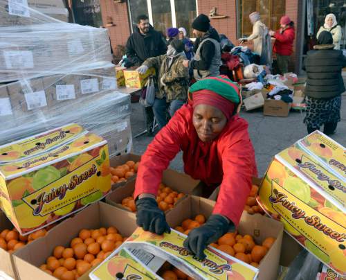 Al Hartmann  |  The Salt Lake Tribune
Mosaic Inter-faith Ministries volunteer Agnes Nduwimana unpacks and organizes food to be given out for holiday food boxes and baskets on Thursday at a multicultural center at 4392 S. 900 E.  Three hundred families received food boxes today.