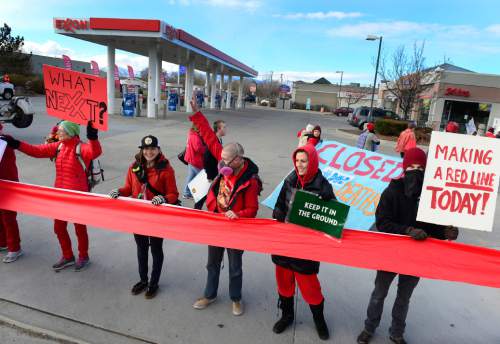 Scott Sommerdorf   |  The Salt Lake Tribune
Environmental activist demonstrators blockaded this Exxon station in Murray with red lines meant to symbolize Exxon's closure, which the activists demand as retribution for the company's alleged role in denying climate change on Saturday.