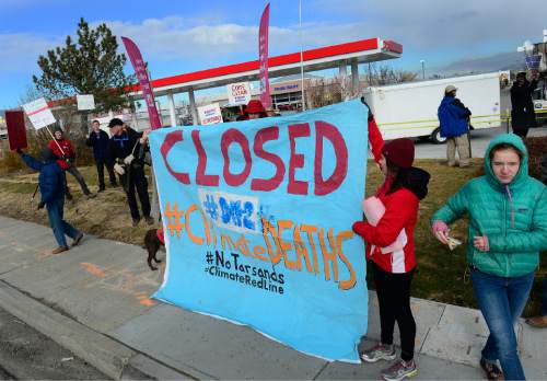 Scott Sommerdorf   |  The Salt Lake Tribune
Environmental activist demonstrators blockaded this Exxon station in Murray with red lines meant to symbolize Exxon's closure, which the activists demand as retribution for the company's alleged role in denying climate change, Saturday, December 12, 2015.