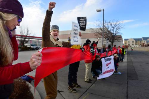 Scott Sommerdorf   |  The Salt Lake Tribune
Environmental activist demonstrators blockaded this Exxon station in Murray with red lines meant to symbolize Exxon's closure, which the activists demand as retribution for the company's alleged role in denying climate change, Saturday, December 12, 2015.