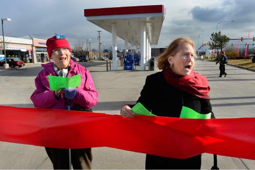 Scott Sommerdorf   |  The Salt Lake Tribune
Gloria Myers, left, and Elise Lazar, right, sing as they and other environmental activist demonstrators blockaded this Exxon station in Murray with red lines meant to symbolize Exxon's closure, which the activists demand as retribution for the company's alleged role in denying climate change, Saturday, December 12, 2015.