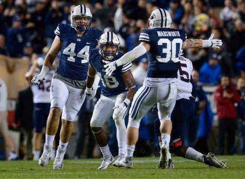 Scott Sommerdorf   |  The Salt Lake Tribune
BYU defensive back Michael Shelton (18) comes up celebrating after intercepting a pass to help seal the BYU win during second half play. BYU beat UCONN 30-13, Friday, October 2, 2015. BYU team mate BYU Michael Wadsworth (30) and Remington Peck (44) help him celebrate.
