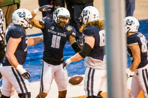 Chris Detrick  |  The Salt Lake Tribune
Utah State Aggies wide receiver Brandon Swindall (11) celebrates with Utah State Aggies offensive lineman Austin Albrecht (65) after scoring a touchdown during the Famous Idaho Potato Bowl at Albertsons Stadium in Boise, Idaho Tuesday December 22, 2015.  Akron Zips defeated Utah State Aggies 23-21.