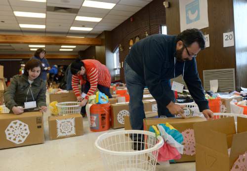 Leah Hogsten  |  The Salt Lake Tribune
Shalom, Salaam – Tikkun Olam's volunteer Emad Sarraj tapes newly packed gift boxes closed for delivery.  Refugee families receive blankets, clothing, coats, hygiene kits, detergent, rice, oil, spices, potatoes, fruit, vegetables and bread on Christmas day. No Christmas themed items are included, yet the items are representative of as unity and celebration of all refugees.  Shalom, Salaam – Tikkun Olam Christmas Day Project, a project that reaches hundreds in need, including 100 refugee families and 350 seniors, as well as residents of area shelters. The charity includes more than 300 volunteers from diverse religious, cultural, and educational backgrounds who prepare and deliver packages made up of food, household goods, gifts, and gift cards, all of which are donated by participating retailers or purchased with donated funds.