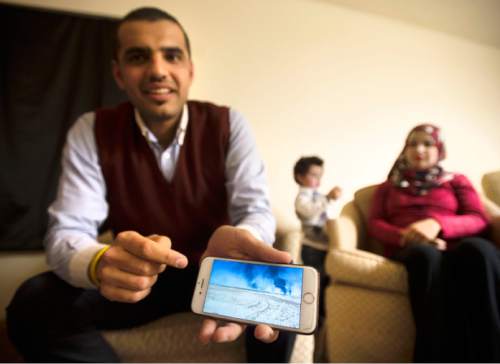 Steve Griffin  |  The Salt Lake Tribune

Holding pictures on his iPhone of oil fields burning near his home in Iraq, Mohammed Alhareb his wife, Sarah Alsahyem, and 2-year-old son, Ridha Alhareb, tell their story in their home in Millcreek on Friday, Dec. 18, 2015.  The family has been in Utah for nine months since leaving Iraq.