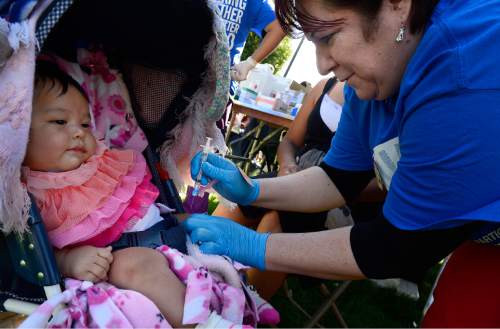 Scott Sommerdorf   |  The Salt Lake Tribune
Selina Ruiz, is given flu shot while still in her stroller by Norma Lamas with Islamic Relief Society at the "Day of Dignity" in Pioneer Park, Sunday, October 11, 2015.