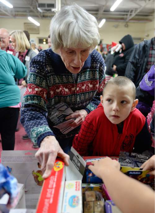 Francisco Kjolseth | The Salt Lake Tribune
Homeless advocate Pamela Atkinson joins Guy Panek, 6, in picking out a Christmas present during the annual Christmas dinner to more than 800 homeless Utahns Friday at St. Vincent de Paul Dining Hall in downtown Salt Lake City.