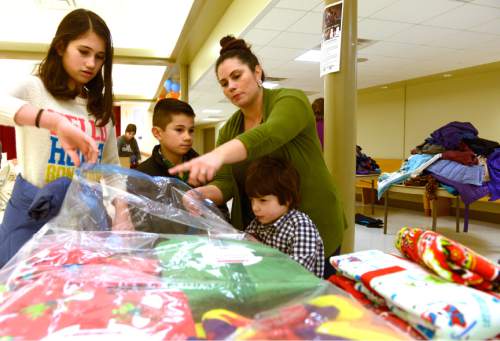 Leah Hogsten  |  The Salt Lake Tribune
Volunteers Tiffany Wharton and her children Violetta, left, 11, Rocco, 8, Salvatore, 5, pack blankets into a vacuum sealable bag at Saint Ambrose Catholic Church for shipment to Kara Tepe refugee camp tent in Lesbos, Greece on Saturday. With the help of the local community and businesses, Erin Freeman raised more than $10,000 to send 1,000 sleeping bags and boots to refugee children at refugee Camp Moria as well as at the ports and on the beaches as the children and their families arrive on the island of Lesbos, Greece, escaping violence in Syria and other neighboring countries.