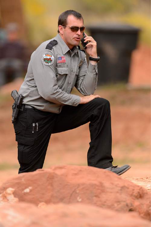 Trent Nelson  |  The Salt Lake Tribune
A Colorado City/Hildale Marshal on the phone at a memorial for the 13 (and 1 still missing) victims of a September 14th flash flood. The memorial was held in Maxwell Park in Hildale, Saturday September 26, 2015.