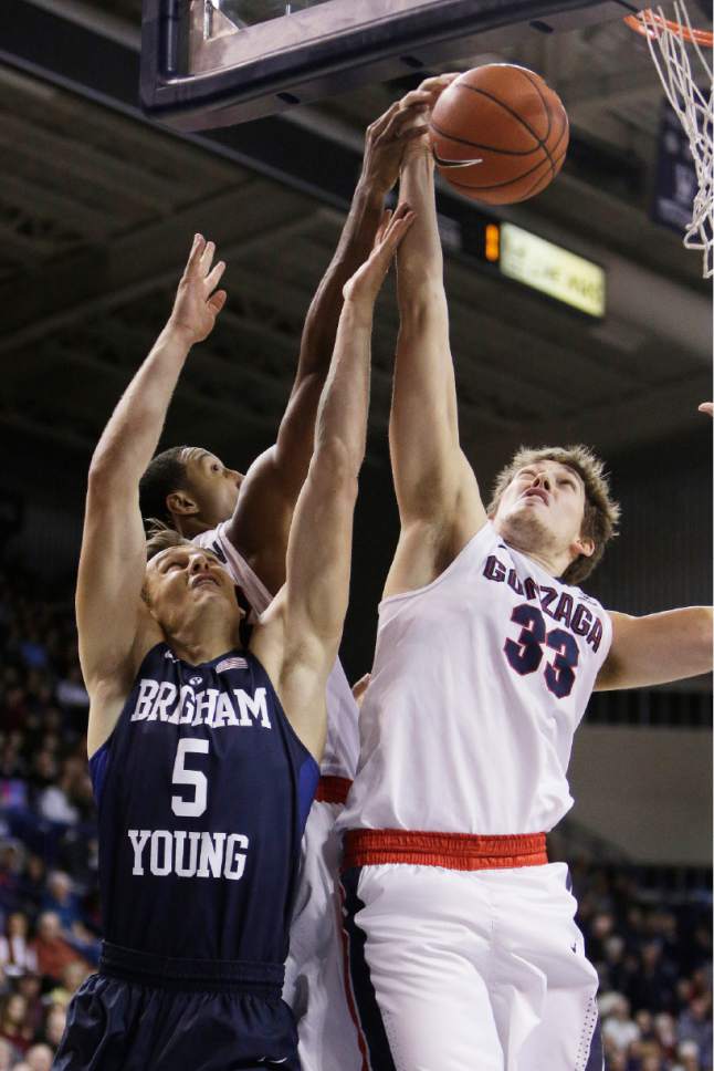 BYU's Kyle Collinsworth (5) goes after a rebound against Gonzaga's Kyle Wiltjer (33) and Eric McClellan during the first half of an NCAA college basketball game, Thursday, Jan. 14, 2016, in Spokane, Wash. (AP Photo/Young Kwak)