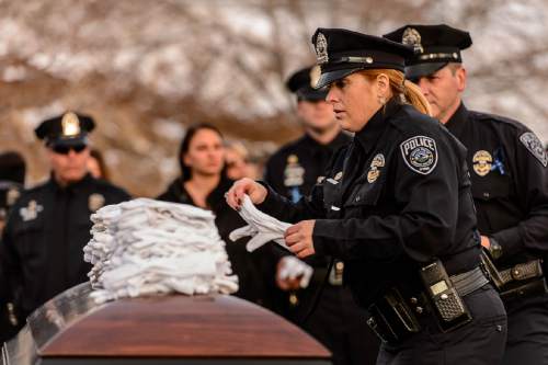 Trent Nelson  |  The Salt Lake Tribune
Officers set down their gloves on the casket at the graveside service for Officer Douglas Scott Barney, at the Orem Cemetery, Monday January 25, 2016.