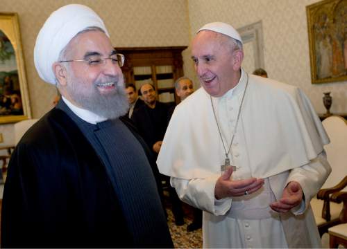 Pope Francis and Iranian President Hassan Rouhani, left, share a laugh during their private audience at the Vatican,Tuesday, Jan. 26, 2016. Iran's president has paid a call on Pope Francis at the Vatican during a European visit aimed at positioning Tehran as a potential top player in efforts to resolve Middle East conflicts, including Syria's civil war. (AP Photo/Andrew Medichini, Pool)
