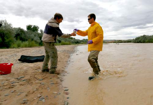 Ben Brown, with the Utah Department of Environmental Quality, left, collects a water sample from the San Juan River from hydrologic technician Ryan Parker, Tuesday, Aug. 11, 2015, in Montezuma Creek, Utah.  A spill containing lead and arsenic from the abandoned Gold King Mine in Silverton, Colo., leaked into the Animas River, which flows into the San Juan River in southern Utah, on Aug. 5. The spill was caused by a mining and safety team working for the EPA.  (AP Photo/Matt York)