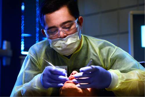 Scott Sommerdorf   |  The Salt Lake Tribune  
Chris Godfrey, a dental student at The Roseman College of Dental Medicine, checks the teeth of a patient at the semi-annual free dental fair at Horizonte organized by the Junior League of Salt Lake City on Saturday.