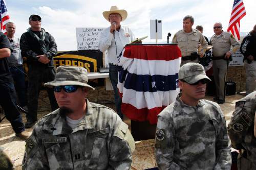 FILE - Rancher Cliven Bundy, middle, addresses his supporters with Clark County Sheriff Doug Gillespie, right, on April 12, 2014. Former Bureau of Land Management director Bob Abbey says Bundy supporters who threatened BLM employees during an armed standoff over the rancher's cattle should be held accountable. (AP Photo/Las Vegas Review-Journal, Jason Bean)